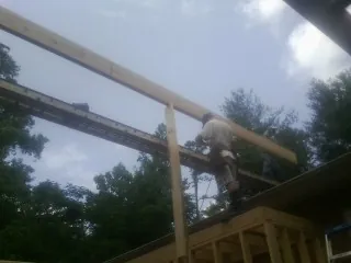 Carpenter setting a ridge beam over a new addition frame — Ice Dam Removal by Roofing Brothers in Munson