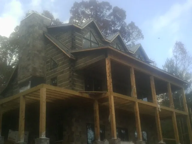 Stone chimney and dormers on a large log home with a timber porch in Munson