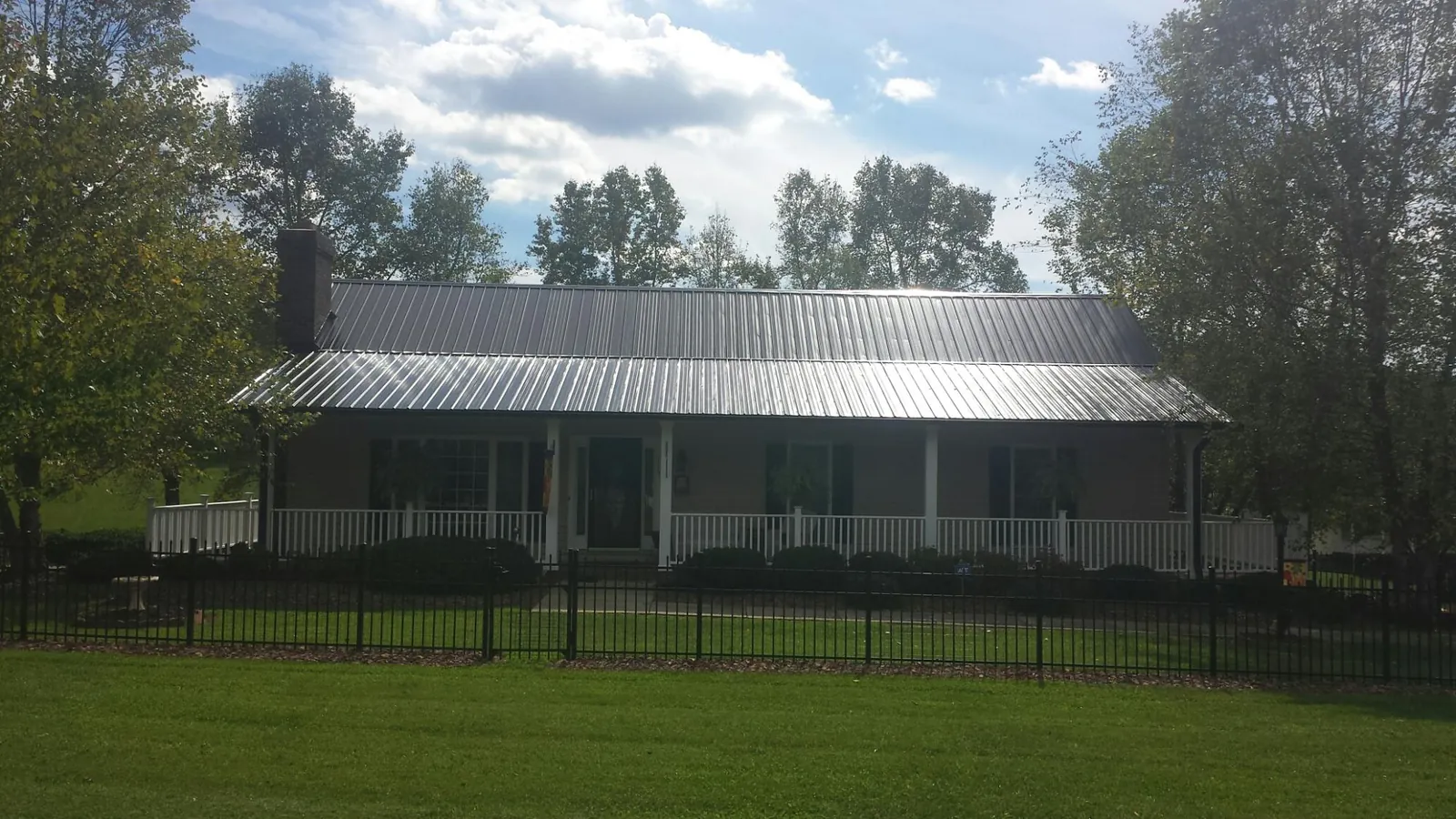 Gray metal roof on a brick ranch with a full width front porch — Gutter Guard Installation work by our crew in Munson