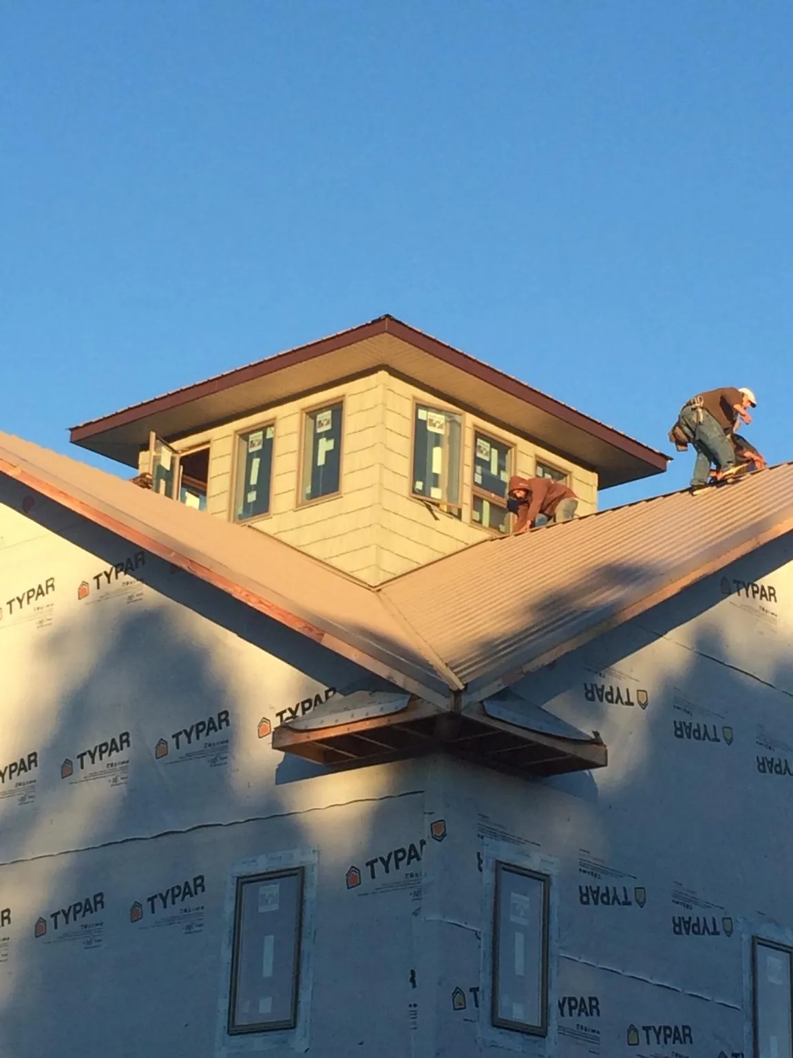 Roofers working around a rooftop cupola on a new metal roof at sunset — Roof Waterproofing in Munson by Roofing Brothers